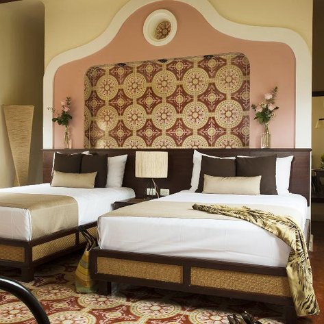 Ein stilvolles Hotelzimmer mit zwei Betten, dekoriert mit einem bunten Wandmuster und eleganten Möbeln.