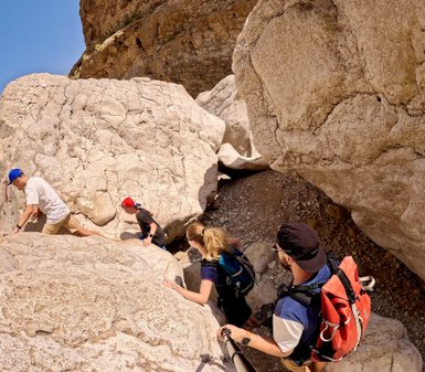 Familie spaziert zwischen Felsen im Wadi Bani Khalid im Oman – Oman Familienreise