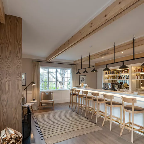 Ein eleganter Barbereich mit hellen Holzregalen, gefüllt mit verschiedenen Spirituosen, und einer einladenden Atmosphäre.