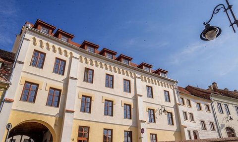 Die Fassade eines eleganten Hotels mit großen Fenstern und einem klaren blauen Himmel im Hintergrund.