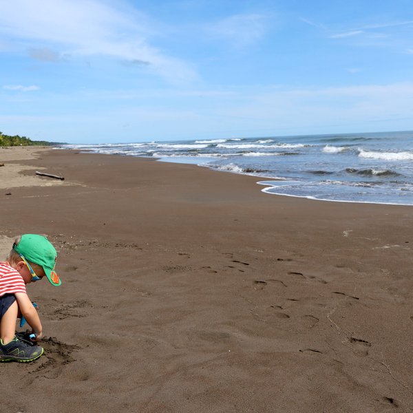 Kind am Sandstrand mit sanften Wellen im Tortuguero Nationalpark – Costa Rica Familienreise