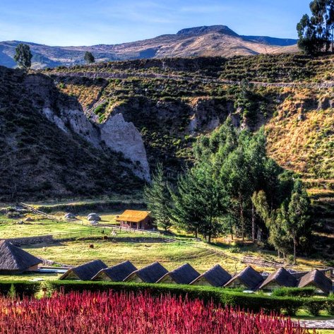 Eine malerische Landschaft mit sanften Hügeln, üppigem Grün und traditionellen Strohdächern in der Ferne.