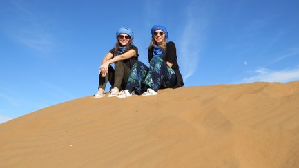 Jugendliche auf einer Sanddüne genießen die Sahara – Marokko mit Kindern