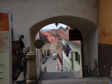 Ein Blick durch einen Torbogen auf eine malerische Straße mit bunten Häusern und einem blauen Himmel im Hintergrund.