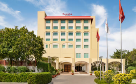 Das Ramada Hotel in Jaipur präsentiert sich mit einer modernen Fassade und einem einladenden Eingangsbereich, umgeben von Grün.