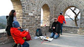 Familie genießt ein gemeinsames Picknick mit Ausblick auf die Chinesische Mauer – China Reise mit Kindern