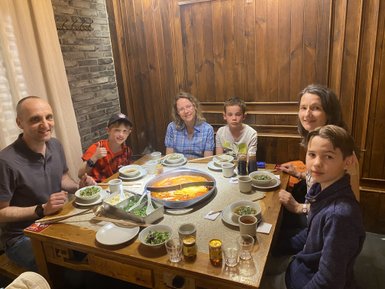 Eine Familie sitzt an einem Tisch und genießt gemeinsam ein heißes Essen in einem gemütlichen Restaurant.