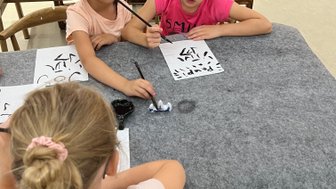 Kinder üben chinesische Kalligrafie auf Papier – China Reise mit Kindern