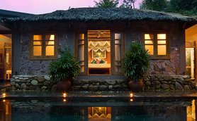 Ein traditionelles vietnamesisches Poolhaus mit einem ruhigen Wasserbecken und sanften Lichtern, umgeben von üppigem Grün.