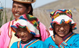 Eine fröhliche Uros-Familie posiert in traditioneller Kleidung auf den schwimmenden Inseln des Titicacasees.