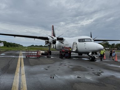 Eine Propellermaschine von Air Panama steht auf einer nassen Landebahn unter einem bewölkten Himmel.