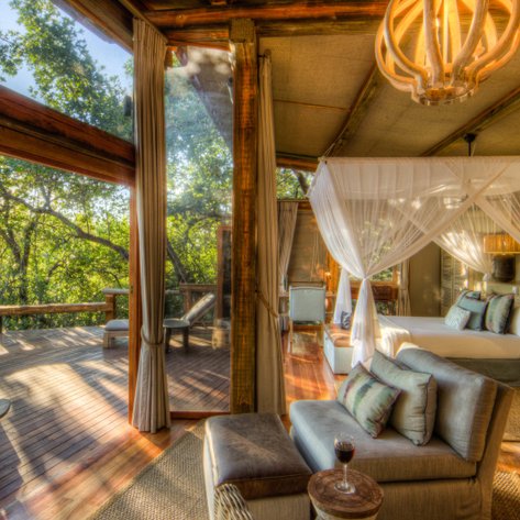Ein elegantes Zimmer mit großen Fenstern, das einen Blick auf die grüne Natur bietet, ideal für Entspannung und Erholung.
