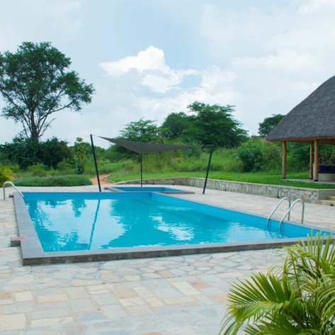 Ein einladender Pool in einer ruhigen Umgebung, umgeben von üppigem Grün und einem schattigen Pavillon.