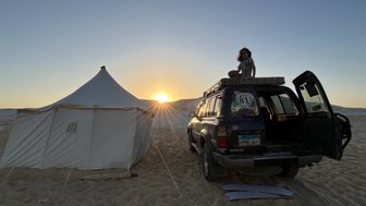 Junge auf einem Jeep in der Weißen Wüste mit Zelten im Hintergrund – Ägypten Reise mit Kindern