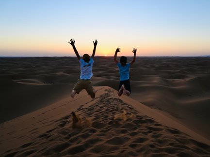 Kinder genießen den Sonnenuntergang beim Springen auf den Dünen der Sahara – Marokko mit Kindern
