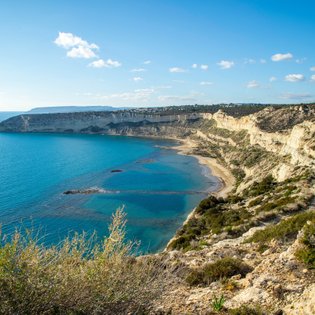 Eine atemberaubende Küstenlandschaft mit klarem, blauem Wasser und sanften Hügeln, die sich entlang der Küste erstrecken.