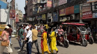 Eine belebte Marktstraße in Alt-Delhi, mit Menschen, die zwischen Ständen und Geschäften umhergehen.