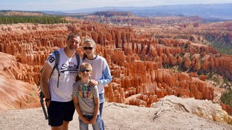 Eine Familie steht am Rand des Bryce Canyon, umgeben von beeindruckenden roten Felsformationen und einer weiten Landschaft.
