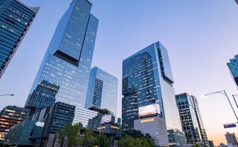 Hochmoderne Wolkenkratzer erheben sich majestätisch gegen den Abendhimmel in Gangnam, Seoul, umgeben von urbanem Leben.