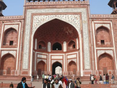 Die majestätische Fassade des Taj Mahal mit kunstvollen Verzierungen und Menschen, die den Eingang passieren.