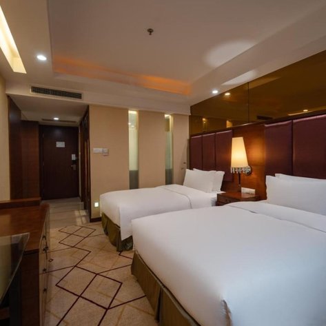 Ein modernes Hotelzimmer mit zwei Einzelbetten, eleganter Beleuchtung und einem Fernseher an der Wand.