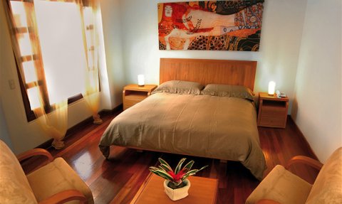 Ein gemütliches Zimmer mit einem großen Bett, sanften Farben und einem Kunstwerk an der Wand, das eine entspannende Atmosphäre schafft.