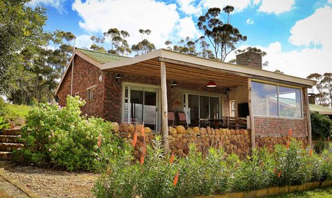 Ein charmantes, gemauertes Ferienhaus mit einem einladenden Garten und einer Veranda, umgeben von üppiger Natur.