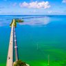 Eine malerische Aussicht auf die lange Brücke, die über das türkisfarbene Wasser von Florida führt, umgeben von üppigem Grün.