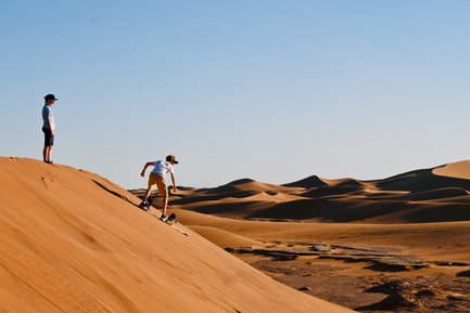 Kinder haben Spaß beim Sandboarding auf den goldenen Dünen – Familienreise mit Kindern