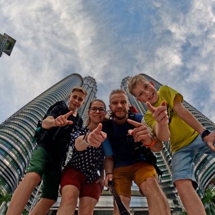 Familie hält einen Moment vor den Petronas Towers in Kuala Lumpur fest – Malaysia & Borneo Familienreise