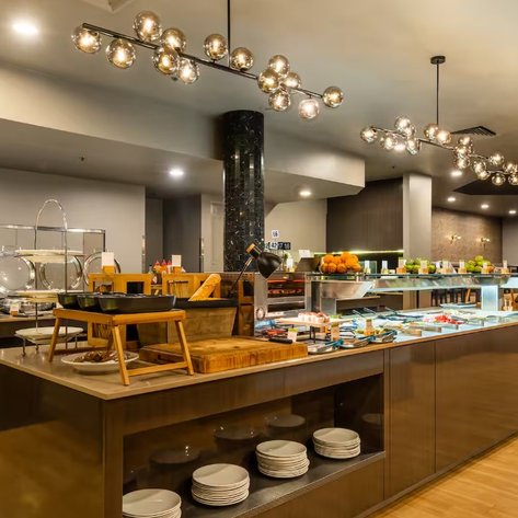 Ein eleganter Buffetbereich zeigt eine vielfältige Auswahl an Speisen, ergänzt durch stilvolle Beleuchtung und modernes Design.