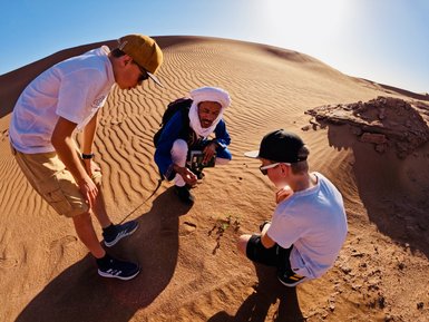 Kinder entdecken zusammen mit einem Guide die Pflanzenwelt in der Sahara – Familienreise nach Marokko