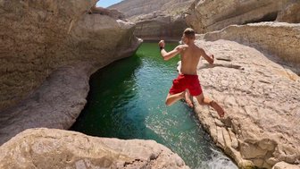 Kind springt ins Wasser im Wadi Bani Khalid – Oman mit Kindern