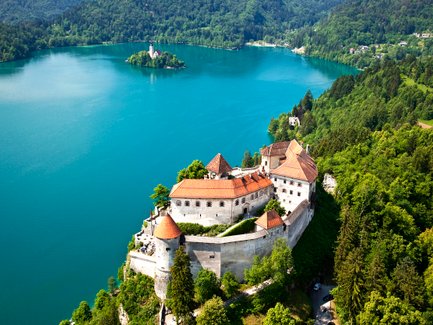 Eine atemberaubende Aussicht auf die Burg Bled, umgeben von üppigem Grün und dem glitzernden Wasser des Sees.