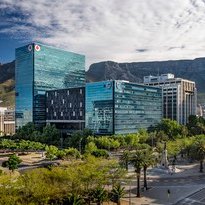 Moderne Wolkenkratzer und grüne Bäume prägen die Stadtlandschaft, während der majestätische Tafelberg im Hintergrund thront.