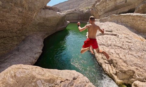Kind springt ins Wasser im Wadi Bani Khalid – Oman mit Kindern