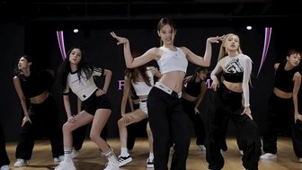 Eine Gruppe von Tänzerinnen in sportlicher Kleidung führt synchronisierte Bewegungen in einem modernen Tanzstudio aus.
