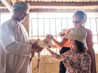 Kinder streicheln Ziege bei einem Farmbesuch im Oman – Oman mit Kindern