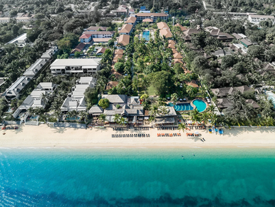 Ein weitläufiger Blick auf das Hotel Bandara Resort in Koh Samui, umgeben von üppigem Grün und dem klaren blauen Wasser.