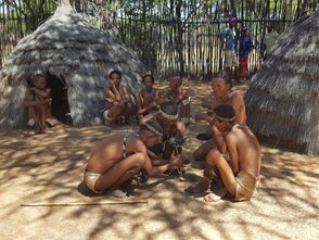 Ein Mann versucht mit einem Holzstab ein Feuer zu entzünden - Namibia Urlaub mit Kindern