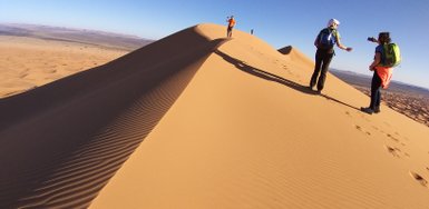 Leute auf Sanddünen der Sahara leuchten im Sonnenlicht – Marokko Familienreise