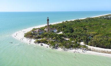 Ein malerischer Blick auf Sanibel Island mit einem Leuchtturm, umgeben von üppigem Grün und einem klaren blauen Wasser.