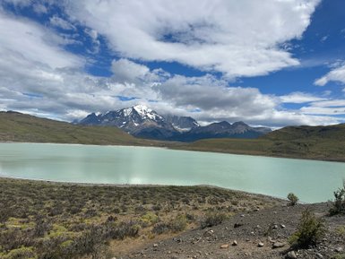 Ein ruhiger See mit grünlichem Wasser spiegelt die majestätischen schneebedeckten Berge im Hintergrund wider.