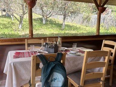 Ein rustikaler Essbereich mit einem Tisch, gedeckt mit Geschirr und einer Wasserflasche, umgeben von einem Garten.