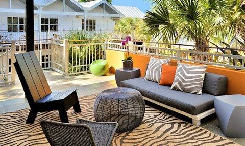 Eine stilvolle Terrasse mit modernen Möbeln, umgeben von Palmen und einem klaren blauen Himmel, lädt zum Entspannen ein.