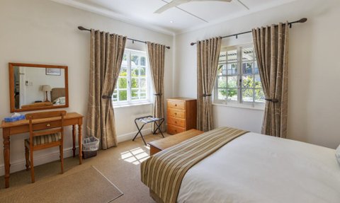 Ein helles Zimmer mit einem großen Fenster, das Tageslicht hereinlässt, und einem gemütlichen Bett mit gestreifter Bettwäsche.
