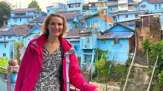 Frau steht vor den markanten blauen Häusern im Dorf – Bali Reise mit Kindern