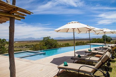 Ein einladender Pool mit Liegen und Sonnenschirmen, umgeben von einer malerischen Landschaft und Bergen im Hintergrund.