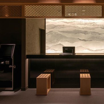 Die elegante Hotelrezeption zeigt eine moderne Gestaltung mit Holz- und Steinelementen sowie einem beruhigenden Wandbild.