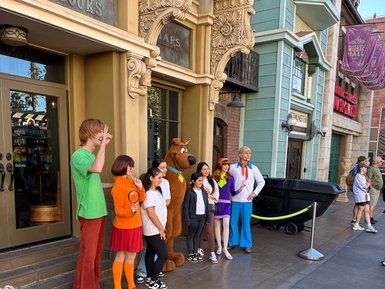 Eine Gruppe von Menschen posiert fröhlich vor einem Gebäude, verkleidet als Charaktere aus Scooby-Doo.